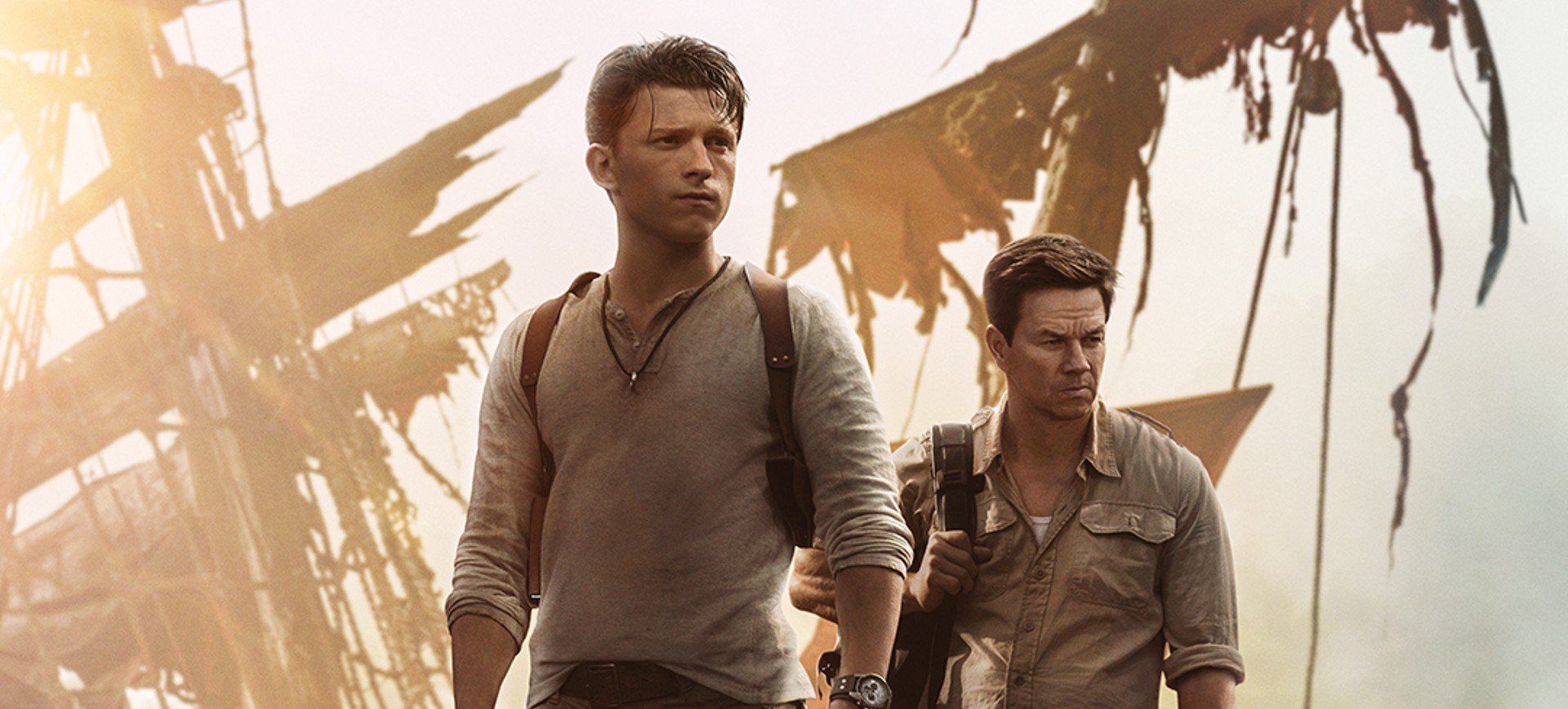 Cena do filme Uncharted Fora do mapa, estrelado pelos atores Tom Holland, que está à esquerda na imagem, e Mark Wahlberg, à direita. Ao fundo há um pedaço do mastro do naufrágio de um barco a vela