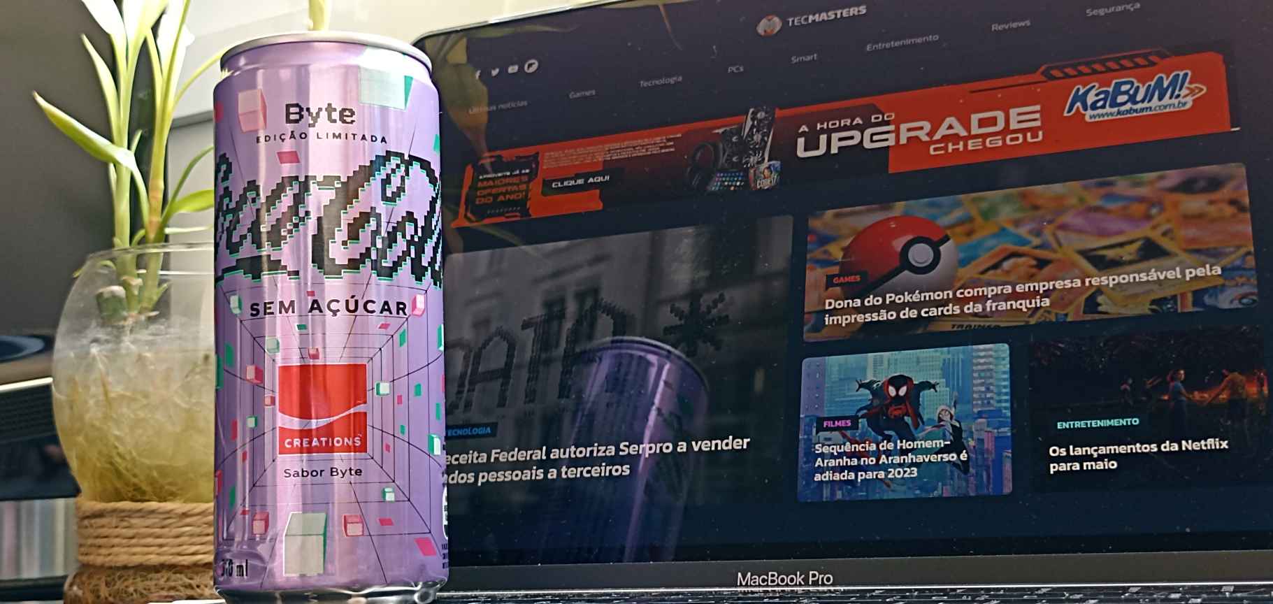 A latinha da Coca-Cola Byte sem açúcar, edição limitada criada no metaverso pela marca; ao fundo o site do blog KaBuM! na tela de um notebook