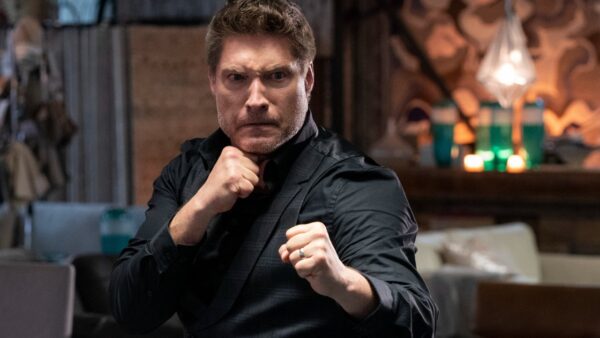 Mike Barnes, vilão vivido por Sean Kanan em Cobra Kai, é mostrado em posição de luta, com os punhos cerrados e vestindo paletó preto com mangas dobradas