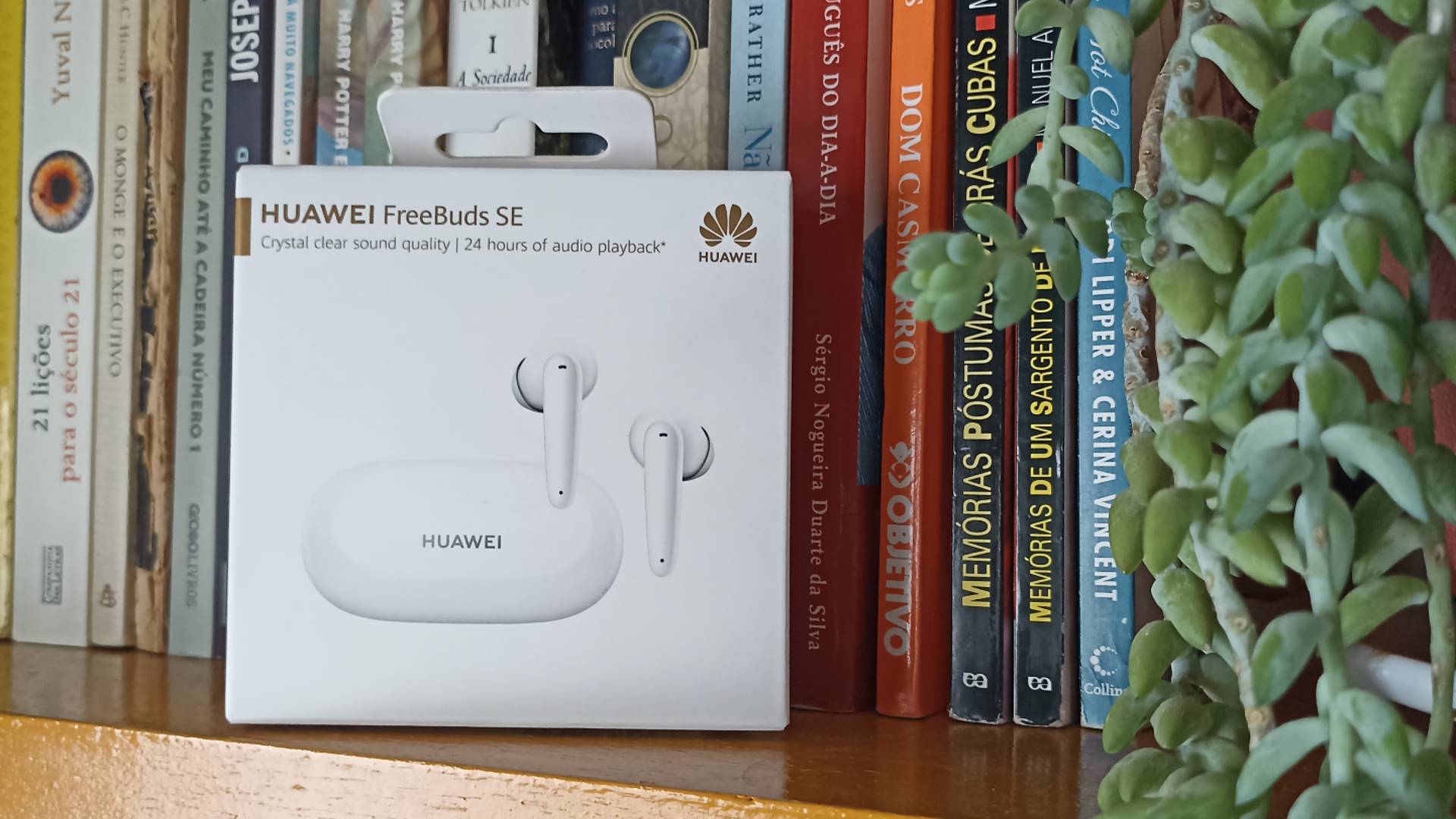 Review Huawei FreeBuds SE - na foto, a caixa do produto em um fundo com livros