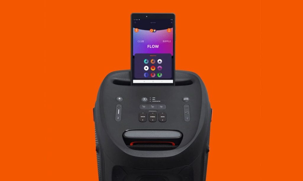 Imagem da caixa de som JBL PartyBox conectada a um smartphone que, por sua vez, mostra a interface do app PartyBox na tela