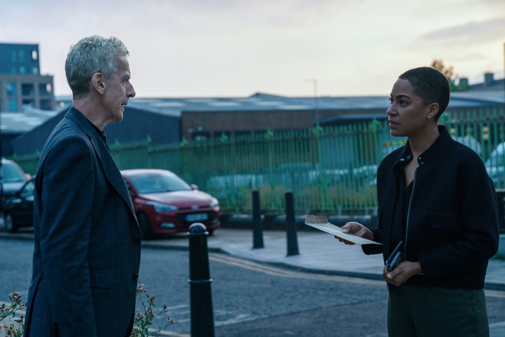 Imagem de divulgação da série Criminal Record, com os atores protagonistas Peter Crepaldi (à esquerda) e Cush Jumbo (à direita), um de frente para o outro como se estivessem conversando e, ao fundo, uma rua em cenário chuvoso. A série é uma das estreias da Apple TV+ para janeiro de 2024