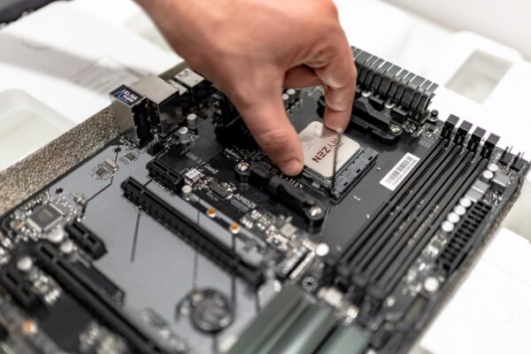 Pessoa aplicando pasta térmica em um processador instalado em uma placa-mãe, destacando os cuidados necessários para a montagem de um PC eficiente.