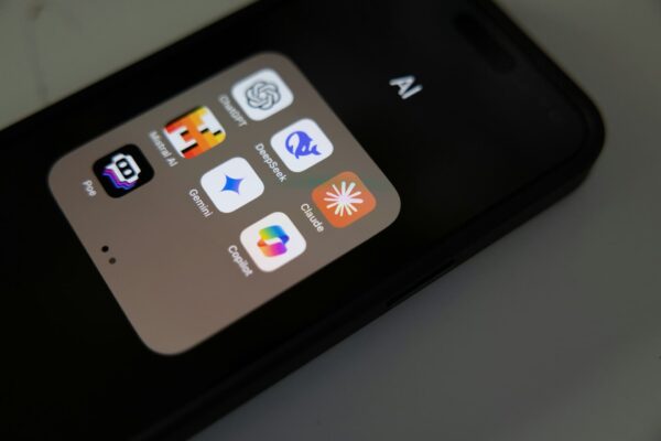 Tela de um smartphone exibindo uma pasta de aplicativos de inteligência artificial (AI). Ícones visíveis incluem ChatGPT, DeepSeek, Claude, Mistral AI, Gemini, Copilot e Poe. O telefone tem um fundo escuro e a imagem destaca a interface organizada desses apps de IA.
